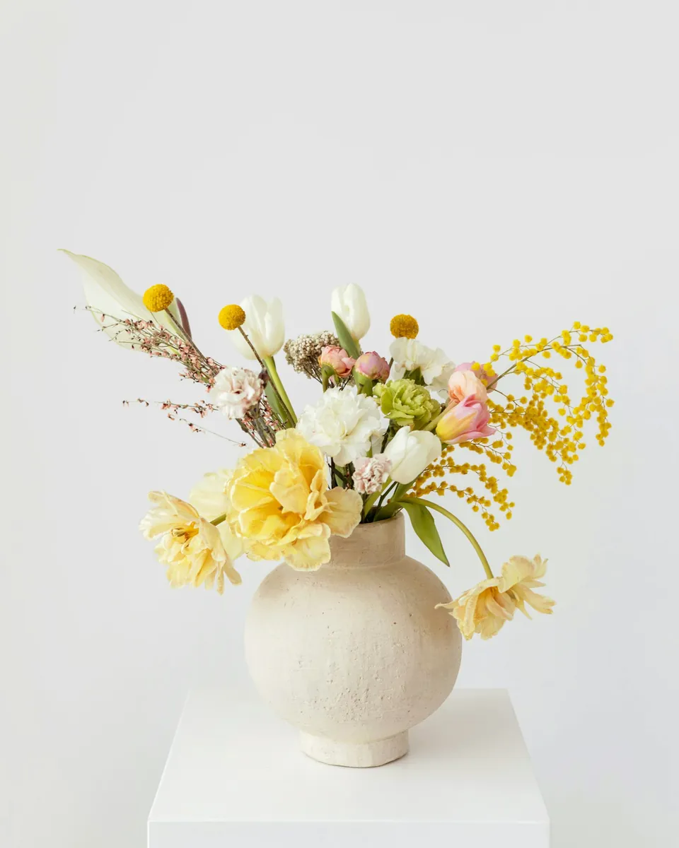 Spring flowers in a ceramic vase on a bright table